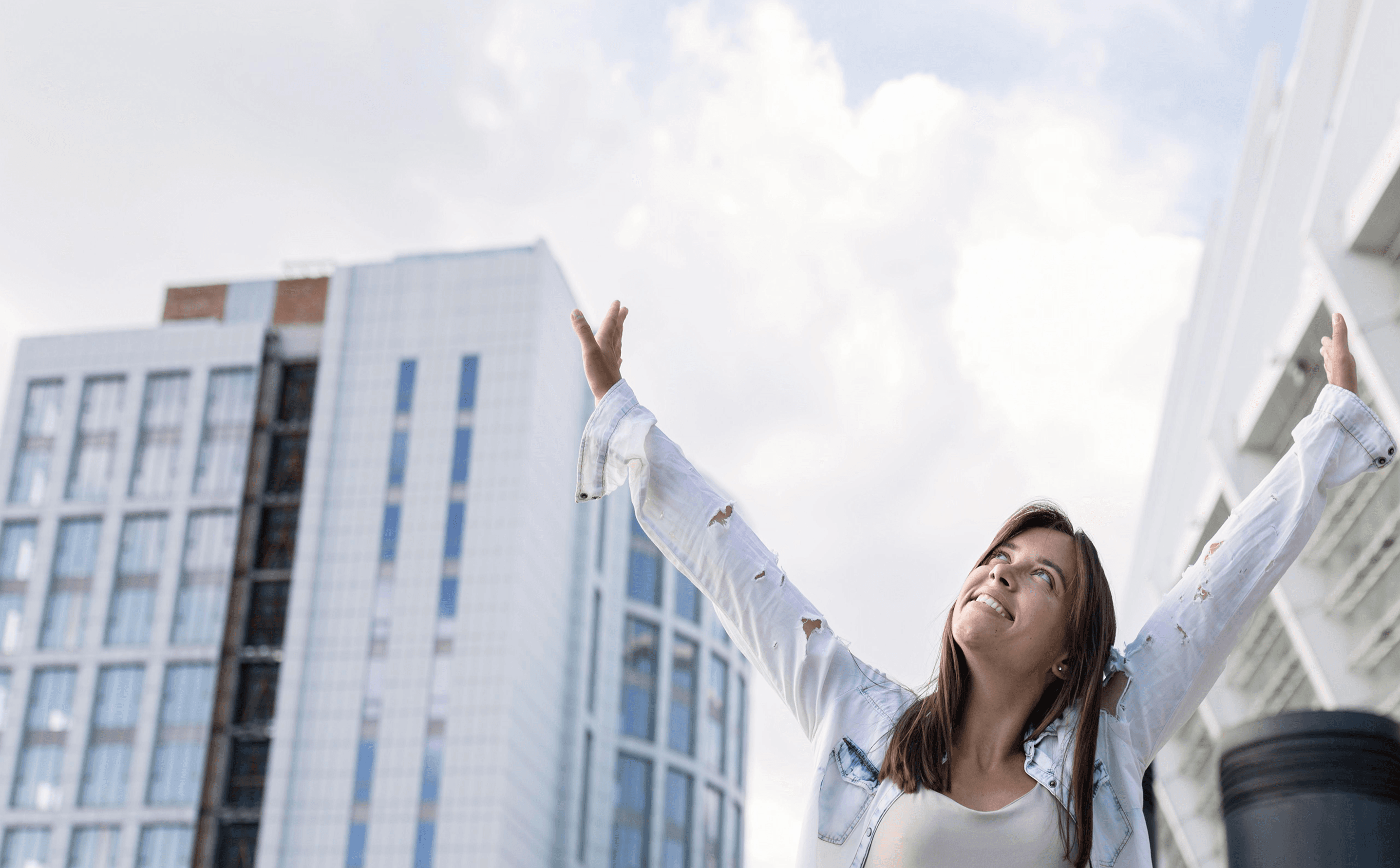 Mujer celebrando frente a edificios modernos